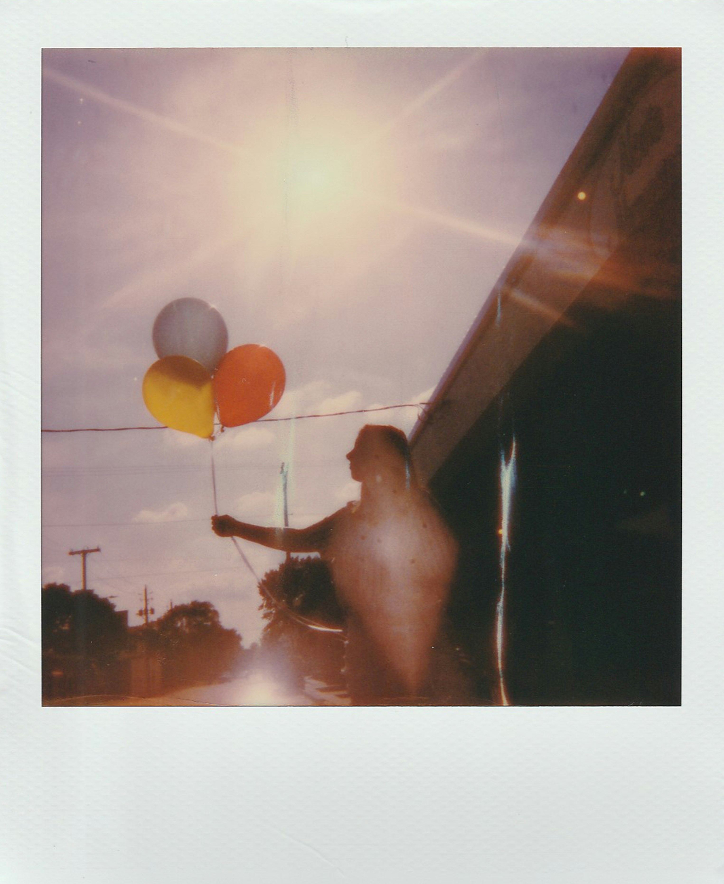 Polaroid of girl holding balloons